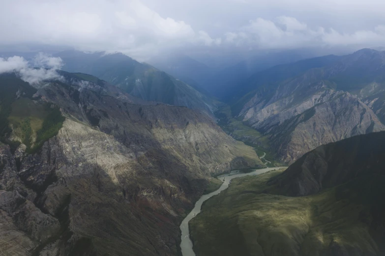 a river running through a valley surrounded by mountains, an album cover, by Muggur, pexels contest winner, hurufiyya, helicopter view, nikolay georgiev, overcast weather, 4 k cinematic panoramic view