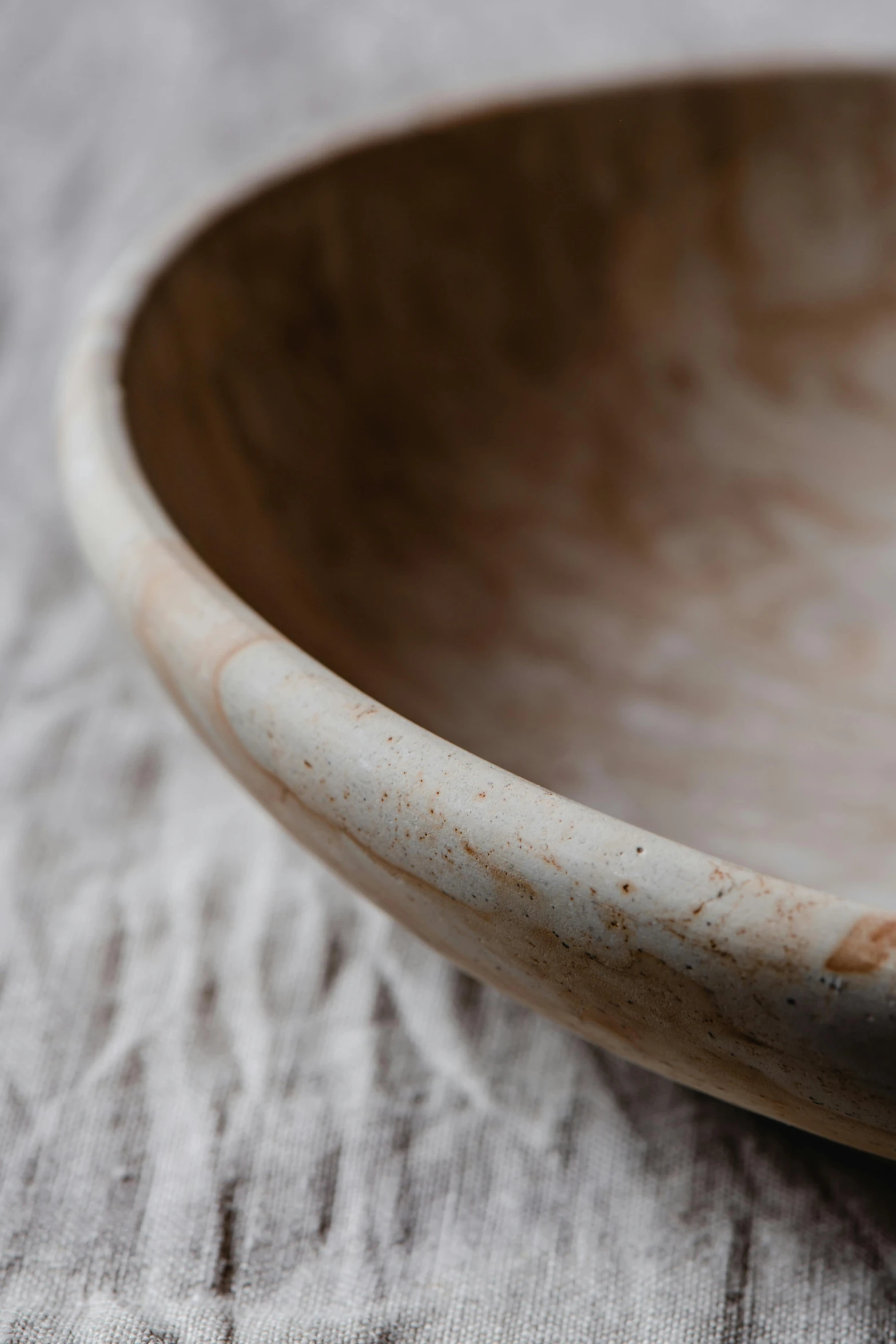 a close up of a wooden bowl on a table, inspired by Fred Williams, unsplash, limestone, beautiful natural soft rim light, half turned around, large shell