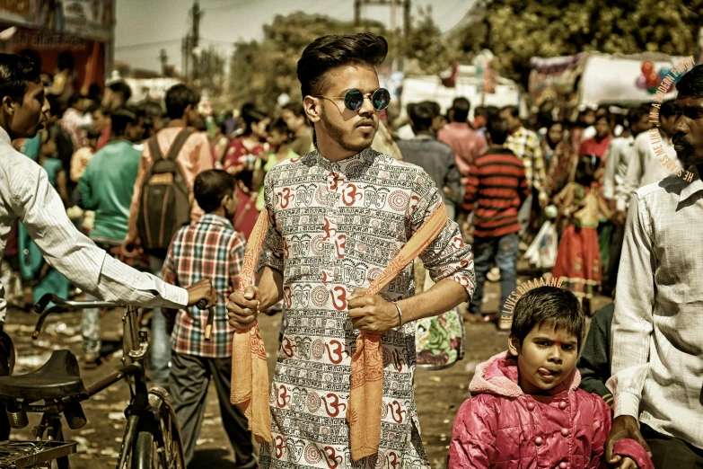 a man standing in front of a crowd of people, an album cover, pexels, samikshavad, patterned clothing, cute boy, on an indian street, modelling