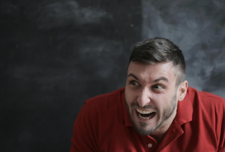 a man with a surprised look on his face, pexels contest winner, red shirt, snarling, on a gray background, achluophobia