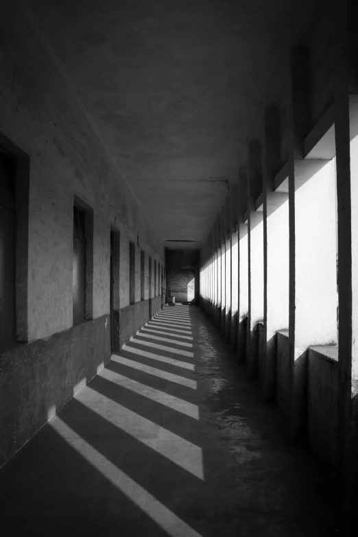 a black and white photo of a long hallway, inspired by Pierre Pellegrini, unsplash contest winner, light and space, sun shafts, deep shadows and colors, colonnade, contre jour