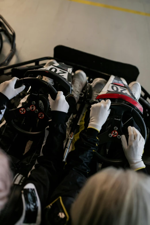 a group of people working on a race car, by Jaakko Mattila, gloves, full frame image, or black, indoor
