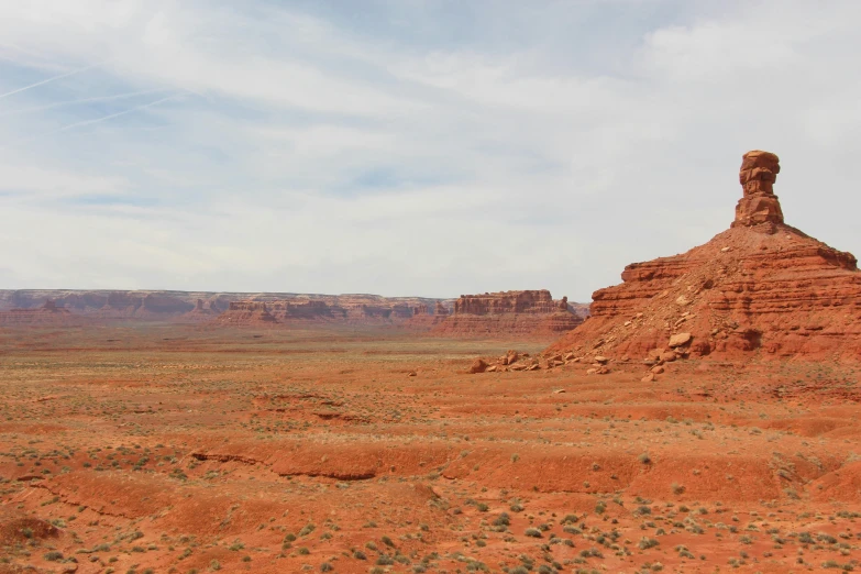 a large rock formation in the middle of a desert, by Jessie Algie, pexels contest winner, panorama distant view, red sandstone natural sculptures, washed out color, green valley below