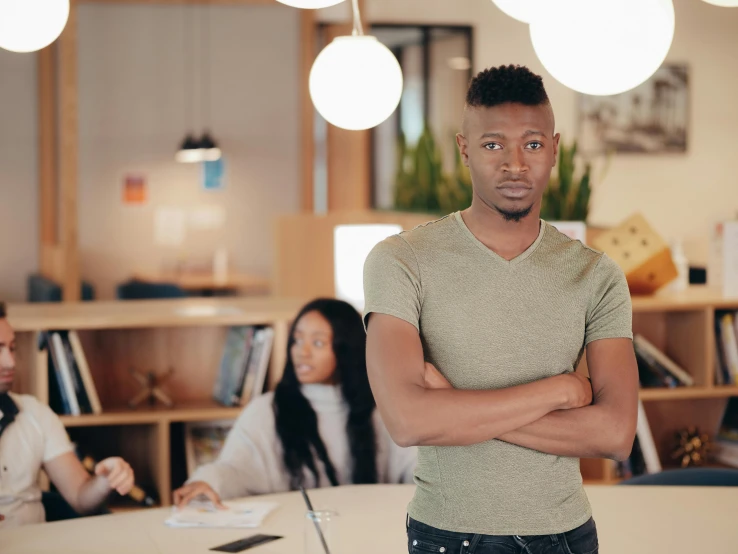 a man standing in an office with his arms crossed, pexels, renaissance, man is with black skin, annoyed, customers, thin young male