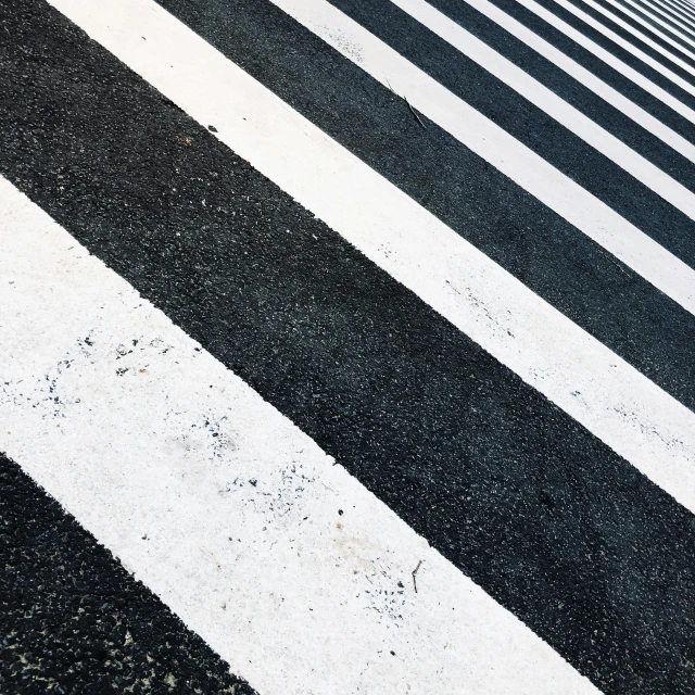 a red fire hydrant sitting on the side of a road, a black and white photo, by Carey Morris, unsplash, hypermodernism, zebra stripes, crossing the line, tokio aoyama, in a row