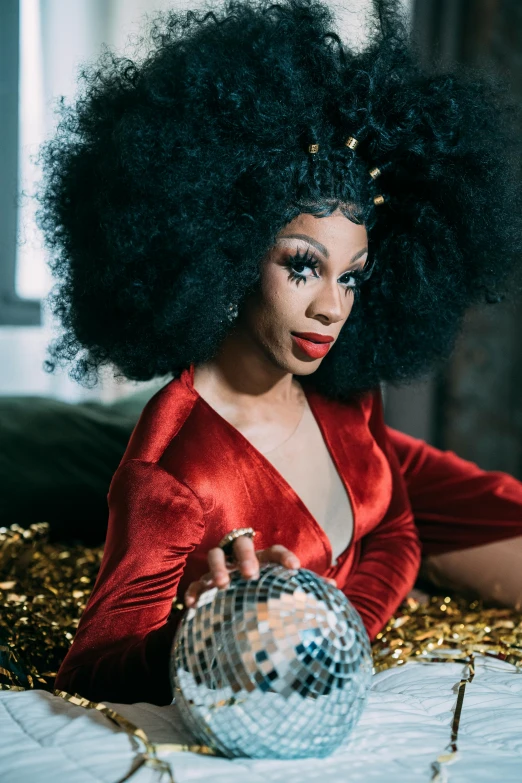 a woman in a red dress holding a disco ball, an album cover, trending on pexels, afrofuturism, wig, proud looking away, black velvet, with a gold crown