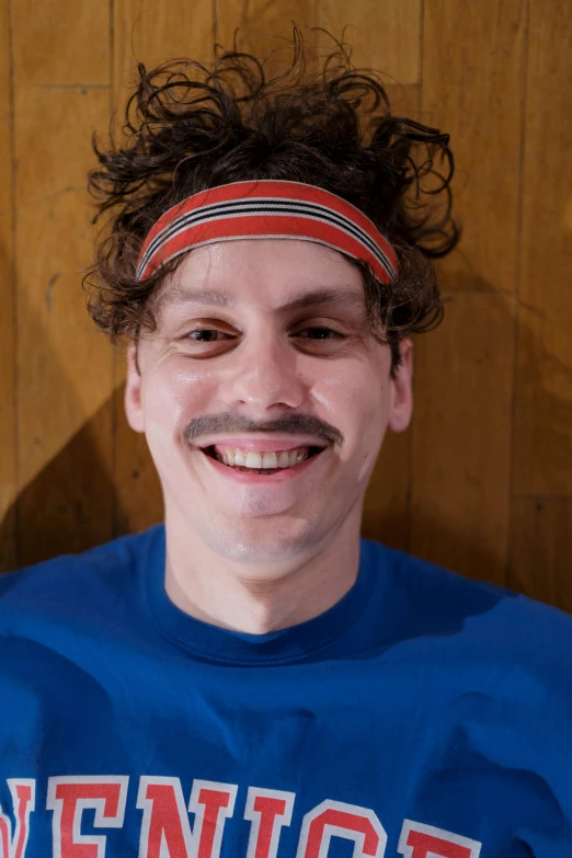 a man with a mustache wearing a blue shirt, inspired by Bernie D’Andrea, trending on reddit, wearing the number 1 headband, pete davidson, andy samberg, high resolution photo