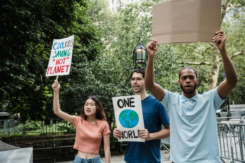 a group of people holding up signs in a park, by Julia Pishtar, pexels, renaissance, 3 - piece, our planet, looking left, cardboard