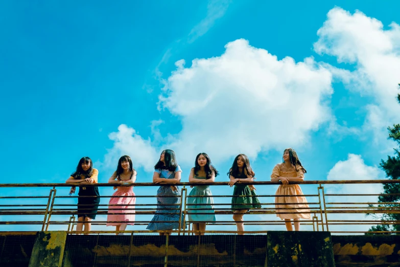 a group of women standing on top of a bridge, an album cover, by Julia Pishtar, pexels contest winner, blue skies, asian women, ( ( theatrical ) ), balcony