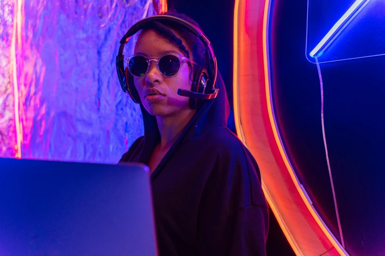 a woman sitting in front of a laptop wearing headphones, cyberpunk art, unsplash, neon standup bar, gaming room, digital sunglasses, penguinz0