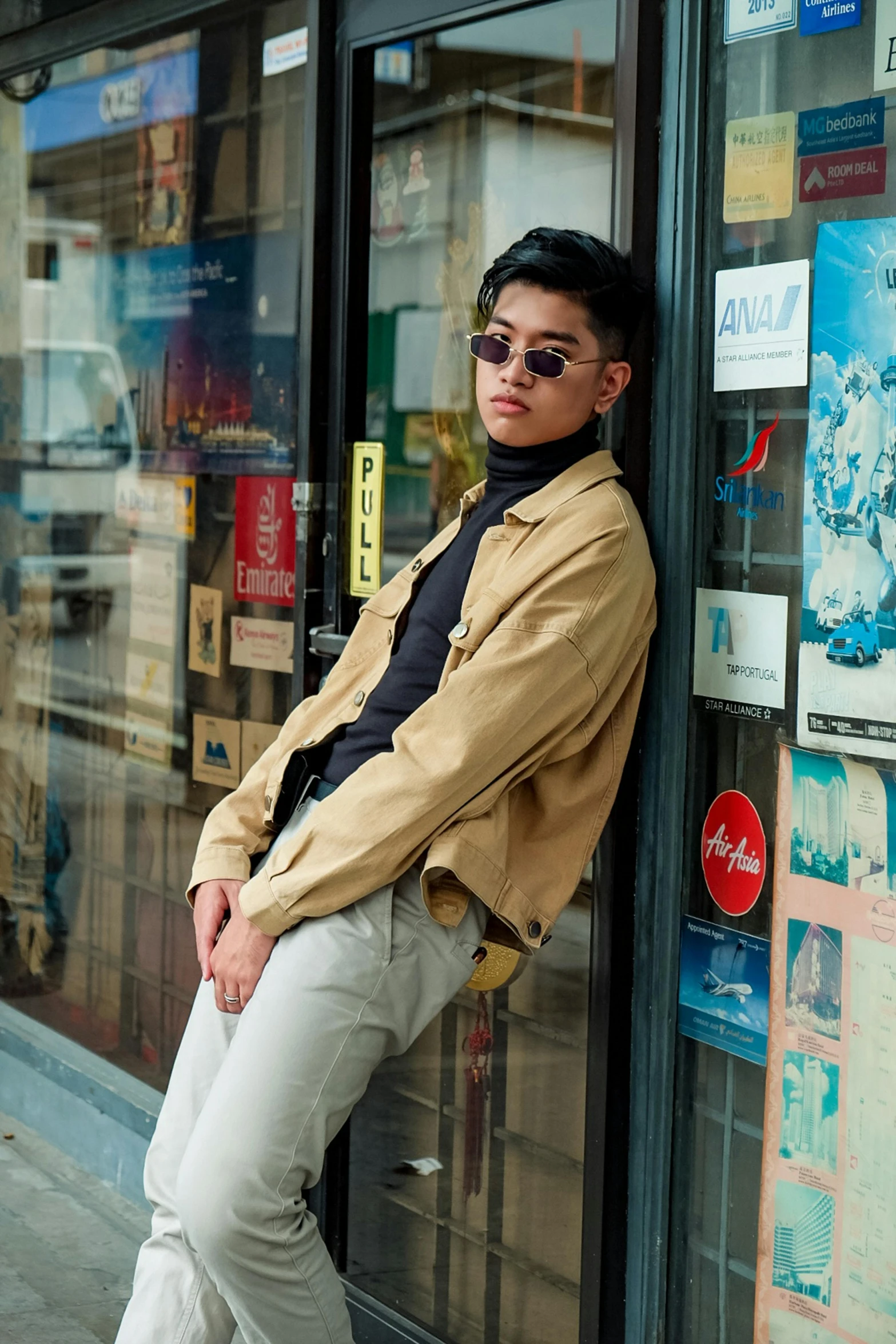 a man leaning against a wall in front of a store, an album cover, pexels contest winner, androgynous person, stanley artgem lau, with sunglass, khakis