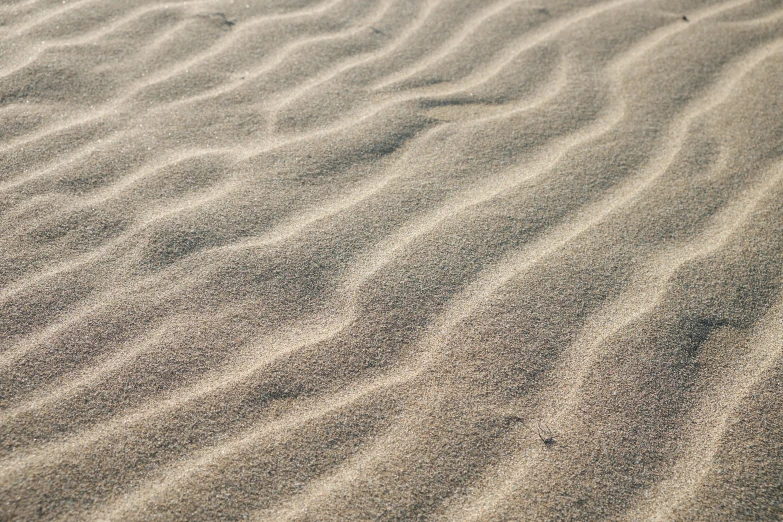 a pile of sand sitting on top of a sandy beach, a stipple, unsplash, minimalism, rippling electromagnetic, subtle patterns, instagram post, up-close