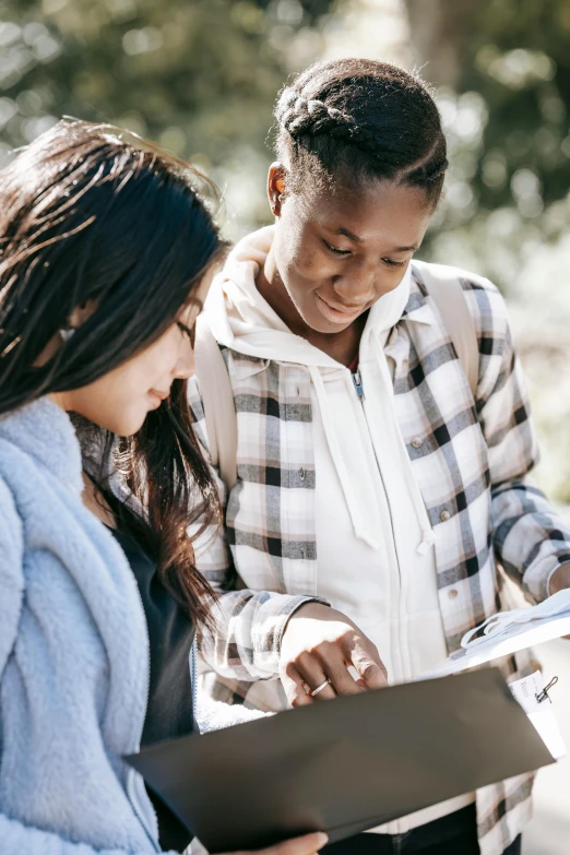 a couple of people standing next to each other, trending on unsplash, happening, holding a clipboard, young girls, lesbian, teaching