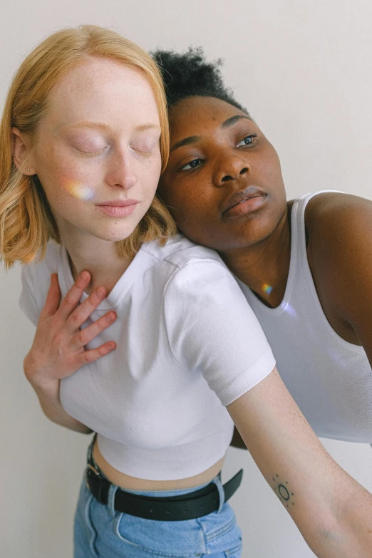 a couple of women standing next to each other, by Carey Morris, trending on pexels, renaissance, iridescent skin, loving embrace, nonbinary model, dressed in a white t-shirt