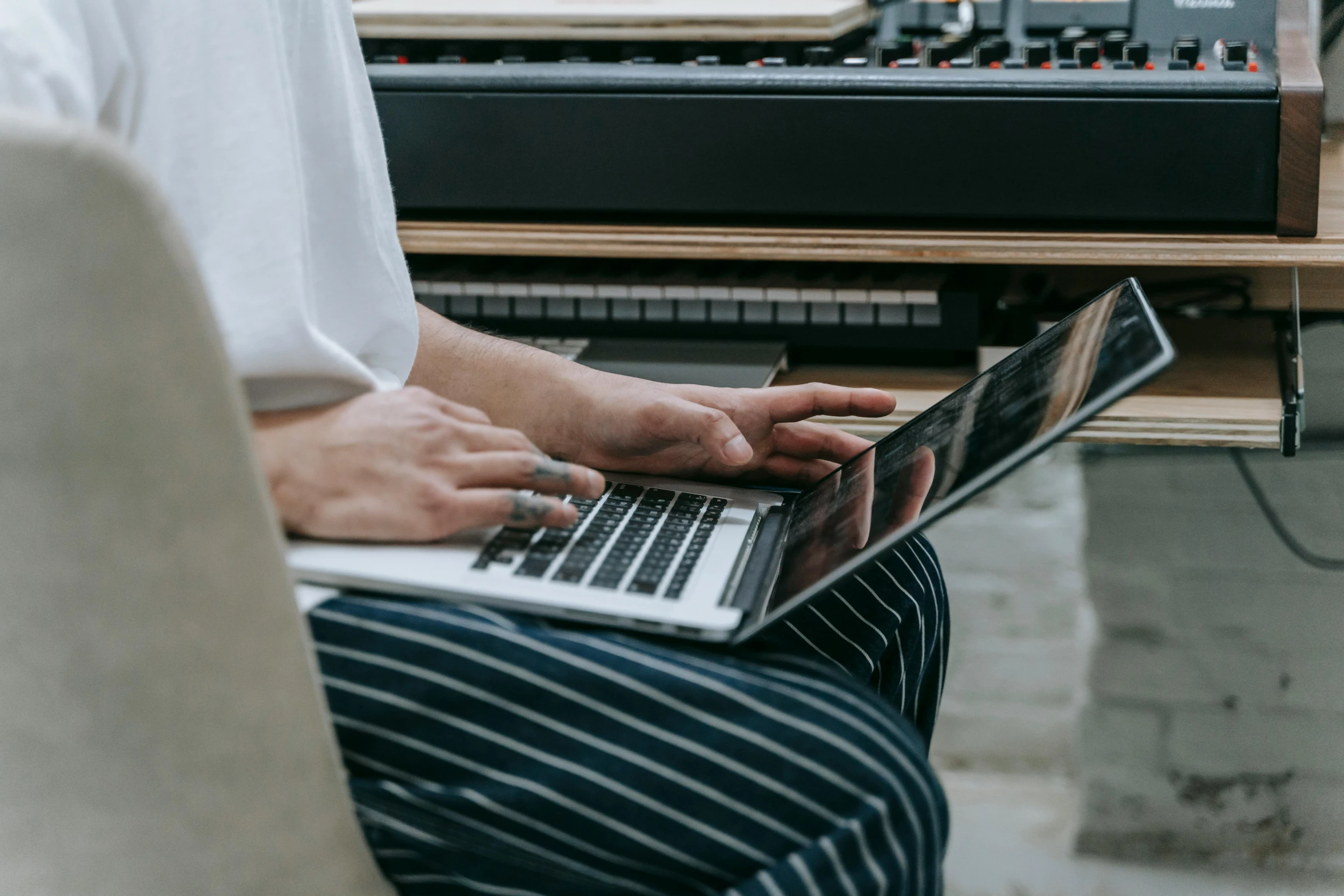 a man sitting in front of a laptop computer, an album cover, trending on pexels, keyboardist, maintenance photo, casually dressed, delicate details