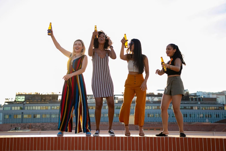 a group of women standing on top of a building, holding beer bottles, yellow, profile image, taken with sony alpha 9