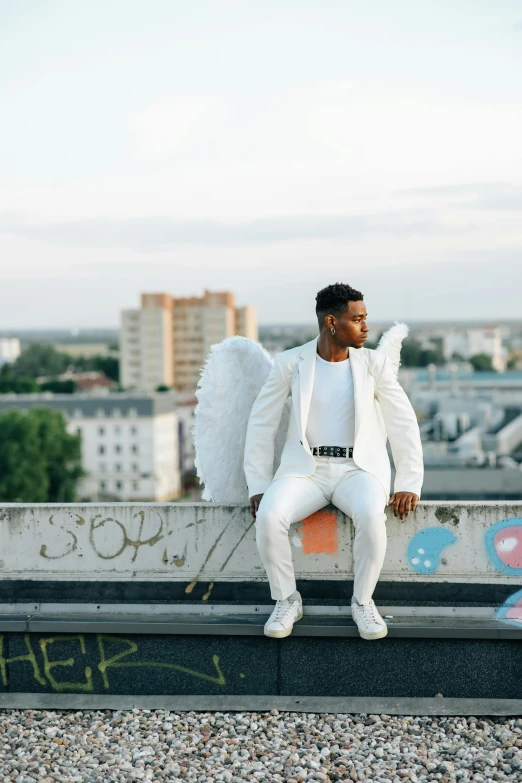 a man in a white suit sitting on a ledge, pexels contest winner, grand angel wings, ashteroth, berlin fashion, cupid