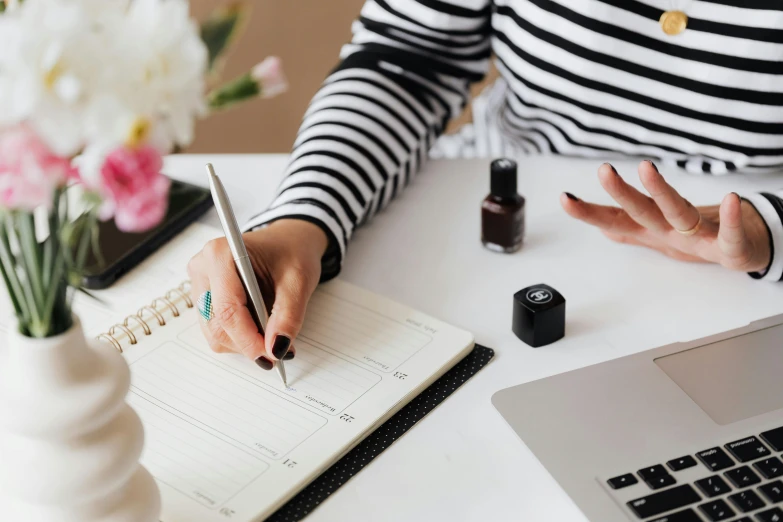 a woman sitting at a desk writing in a notebook, trending on pexels, black nails, wearing stripe shirt, female calendar, walking down