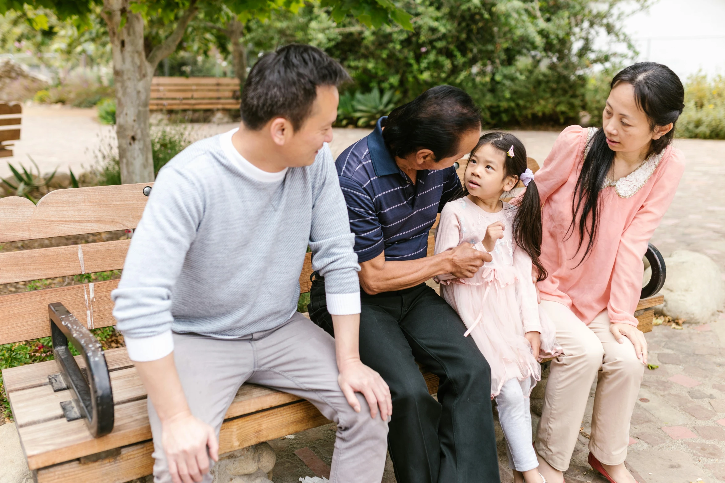 a family sitting on a bench in a park, pexels contest winner, happening, asian descent, caring fatherly wide forehead, giggling, te pae