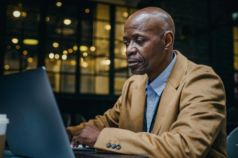 a man sitting in front of a laptop computer, by Joseph Severn, pexels contest winner, augusta savage, colour photo, 50 years old men, elegantly dressed