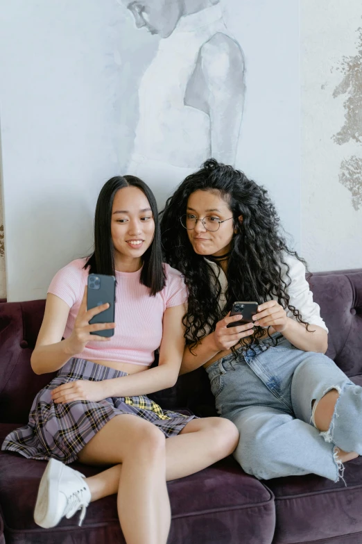 two women sitting on a couch looking at their cell phones, trending on pexels, renaissance, asian girl with long hair, non binary model, proud looking, teen magazine cover