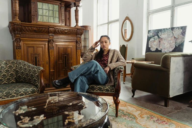 a woman sitting in a chair in a living room, a portrait, inspired by Fei Danxu, pexels contest winner, androgynous person, old furniture, full body photo, ashteroth