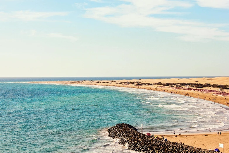 a group of people standing on top of a sandy beach, by Julia Pishtar, pexels contest winner, happening, ocean shoreline on the horizon, oman, reefs, hollister ranch