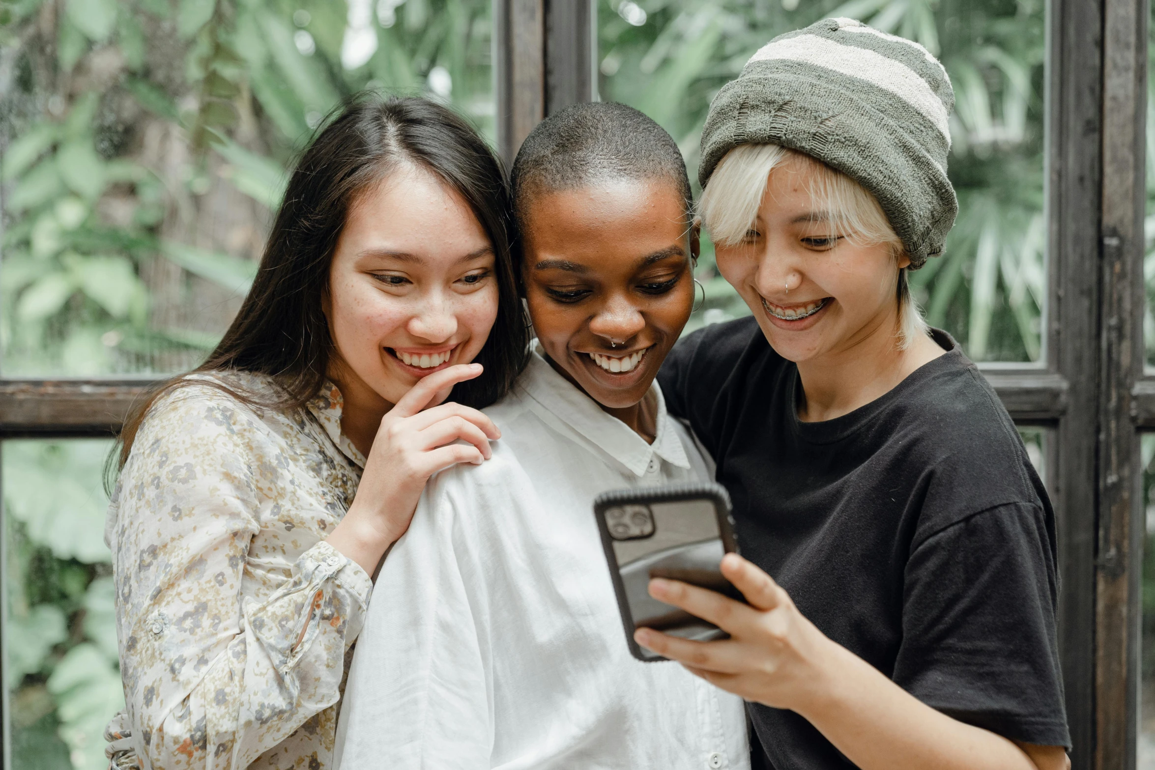 a group of women standing next to each other looking at a cell phone, trending on pexels, avatar image, lovingly looking at camera, three women, diverse