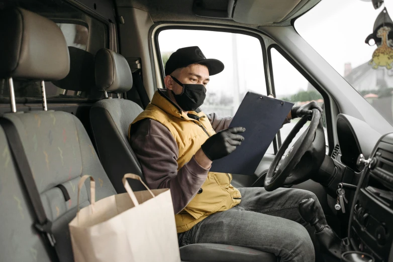 a man sitting in the driver's seat of a van, wearing facemask, delivering mail, charcoal and yellow leather, avatar image