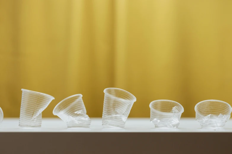 a row of plastic cups sitting on top of a table, by Sven Erixson, clear curvy details, product shoot, overturned chalice, varying angles