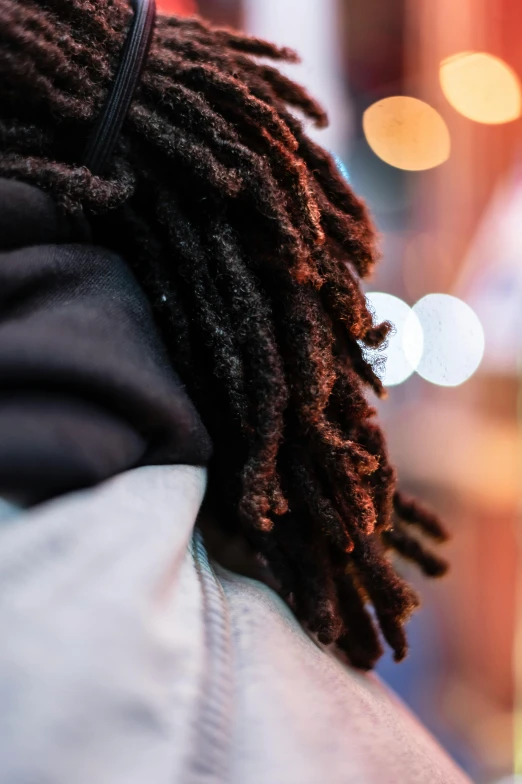 a close up of a person with dreadlocks, street clothing, over his shoulder, curls and curves, uplit