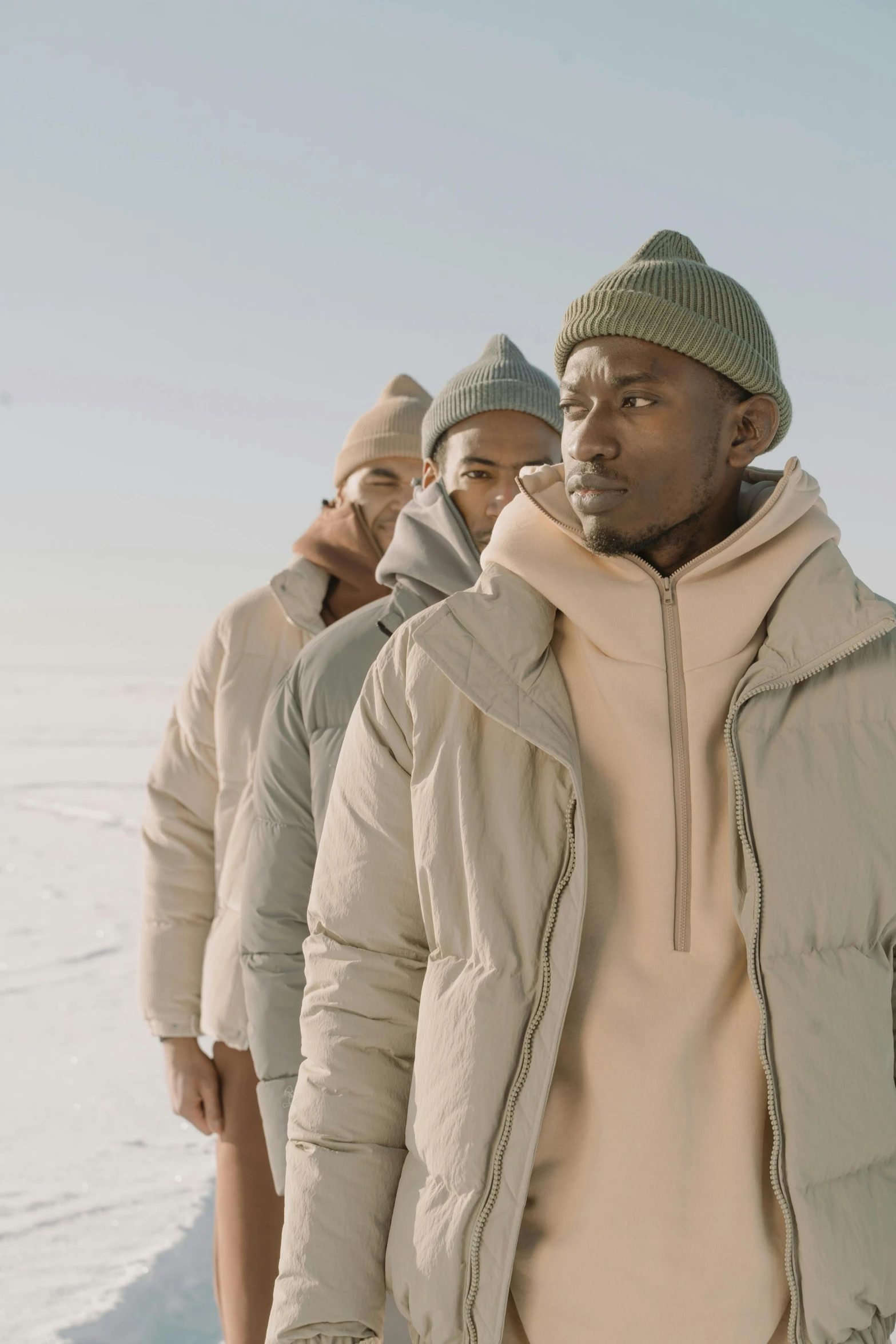 a group of men standing next to each other in the snow, inspired by Barthélemy Menn, trending on pexels, model wears a puffer jacket, muted colour, video still, kano)