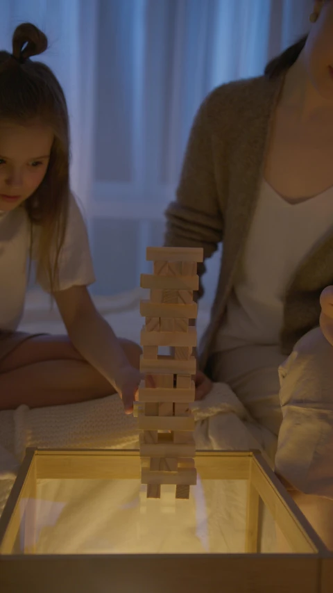 a woman and a little girl playing with wooden blocks, pexels contest winner, conceptual art, night time footage, unreal engine. film still, the great marble wizards tower, in the bedroom at a sleepover