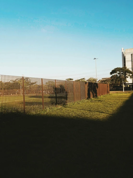 a man riding a skateboard on top of a lush green field, inspired by Elsa Bleda, realism, rusty chain fencing, instagram story, location ( favela _ wall ), brown