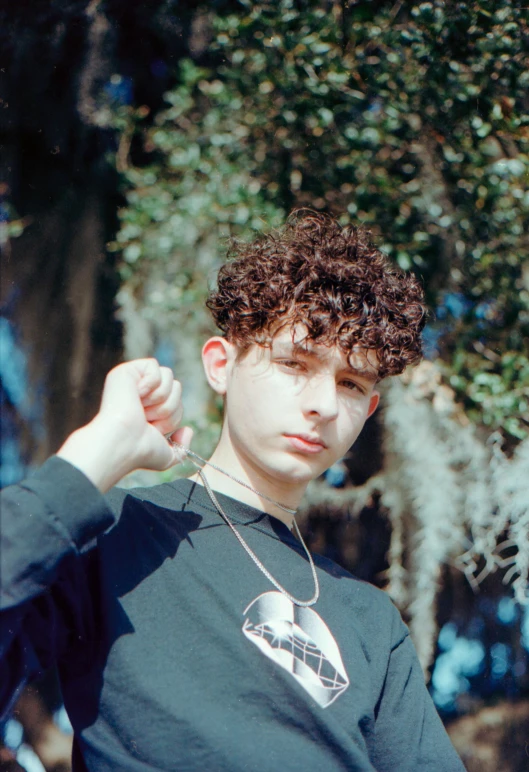 a young man with curly hair posing for a picture, an album cover, inspired by Jean Malouel, trending on pexels, 1990s photograph, gal yosef, curly bangs, 2 1 savage