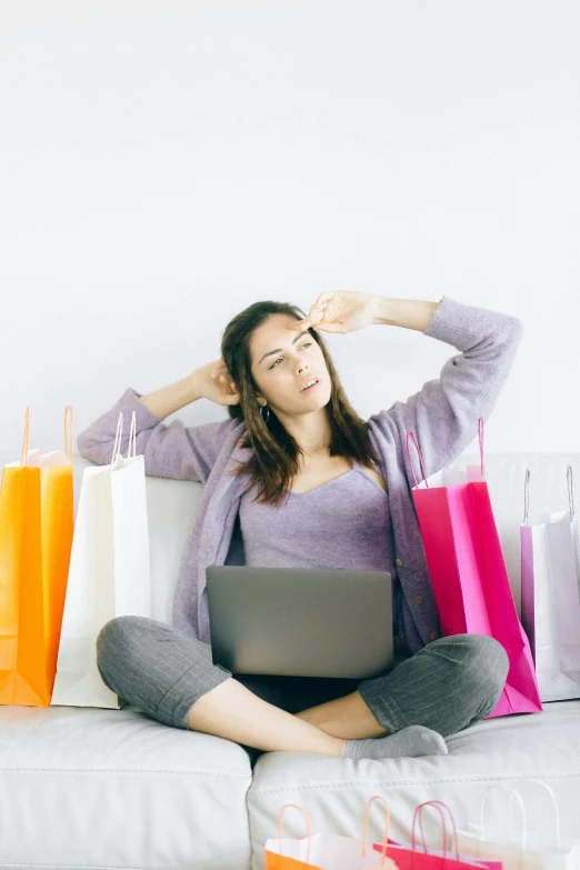 a woman sitting on a couch with shopping bags, a colorized photo, trending on pexels, sitting in an empty white room, stressing out, in front of the internet, promotional image