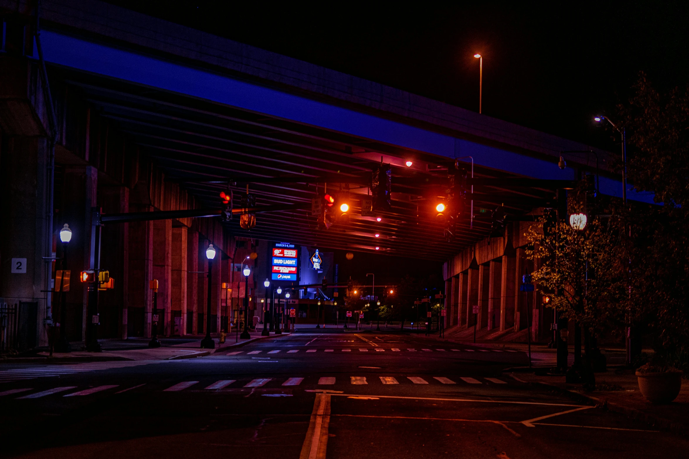 a street filled with lots of traffic at night, a picture, unsplash, realism, red and blue black light, under bridge, empty streetscapes, coventry city centre