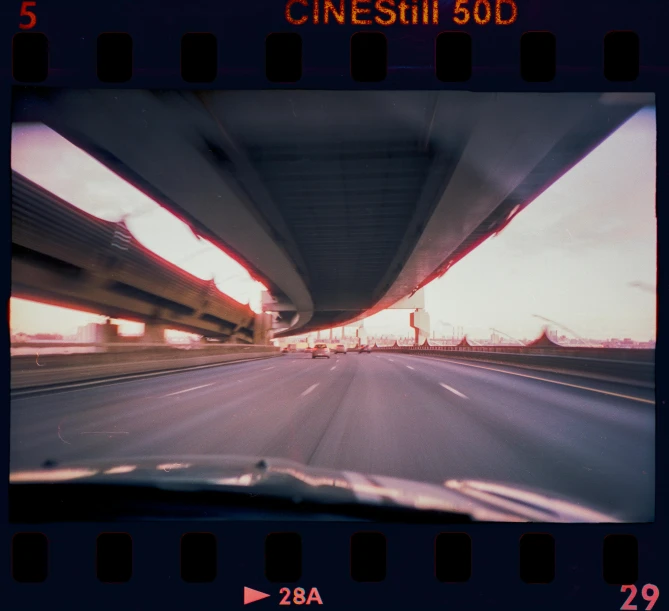 a car driving down a highway under a bridge, a polaroid photo, unsplash, video art, \!cinestill 50d! film photo, vhs distortions, medium format film photography, wideangle pov closeup
