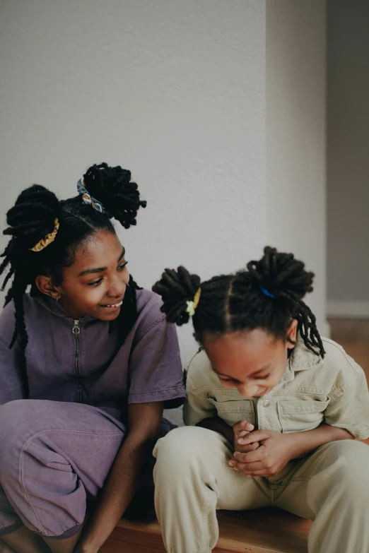 a couple of young girls sitting on top of a wooden floor, by Lily Delissa Joseph, pexels contest winner, black arts movement, braided hair loops, bedhead, educational, dreads