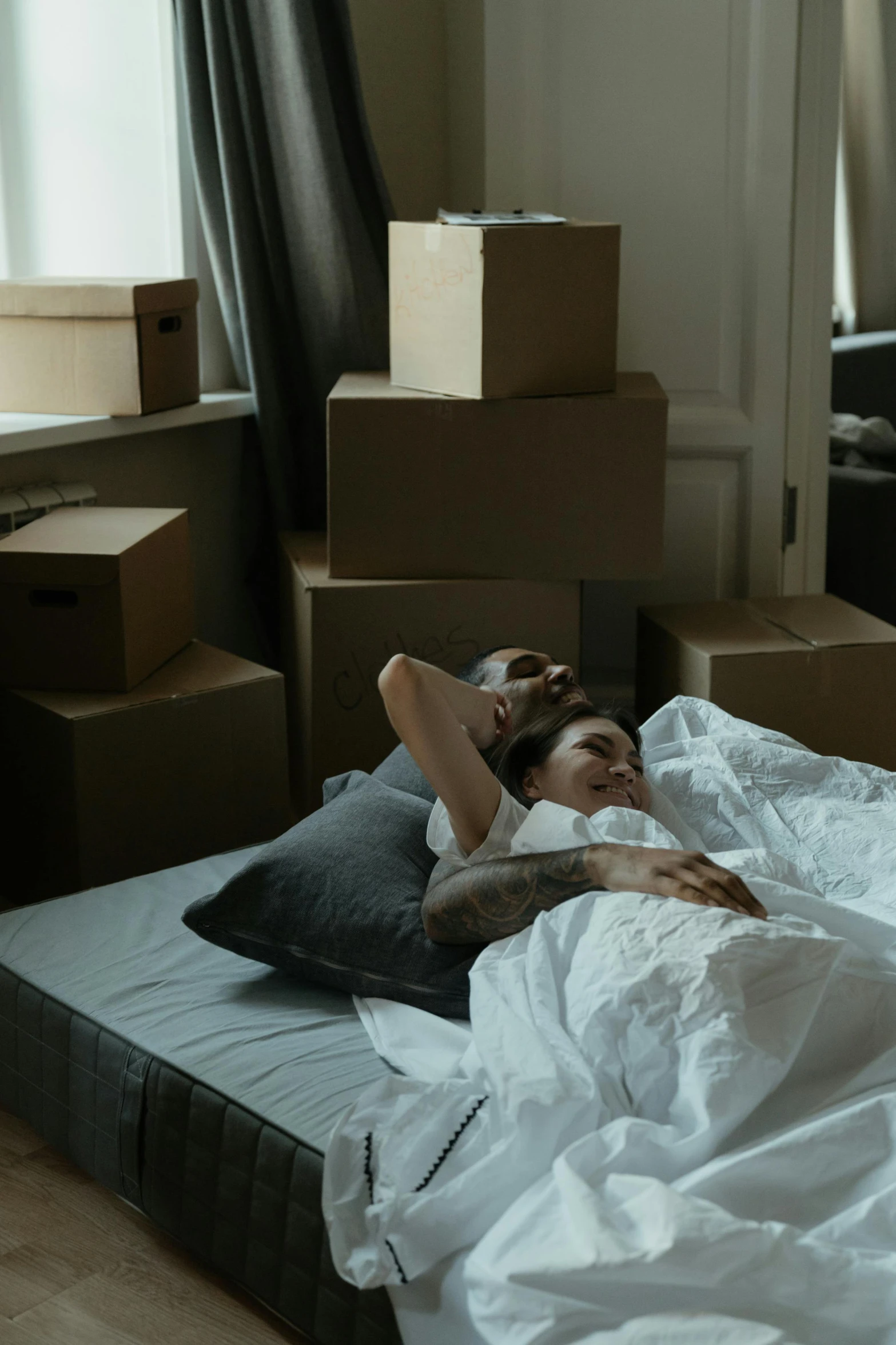 a couple of people laying on top of a bed, packaging, long distance, bulky build, dark bedroom