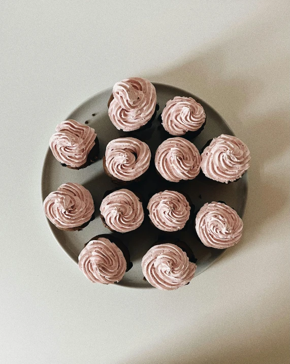 a black plate topped with cupcakes on top of a white table, by Helen Stevenson, unsplash, faded pink, organic rippling spirals, taken on iphone 14 pro, low quality photo