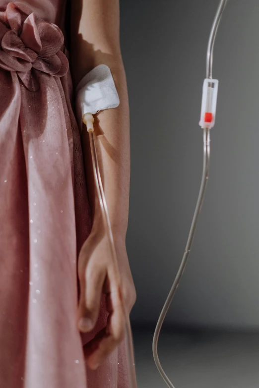 a woman in a pink dress holding an ivg, inspired by Méret Oppenheim, unsplash, surgical iv drip, wax figure, getty images, kidney