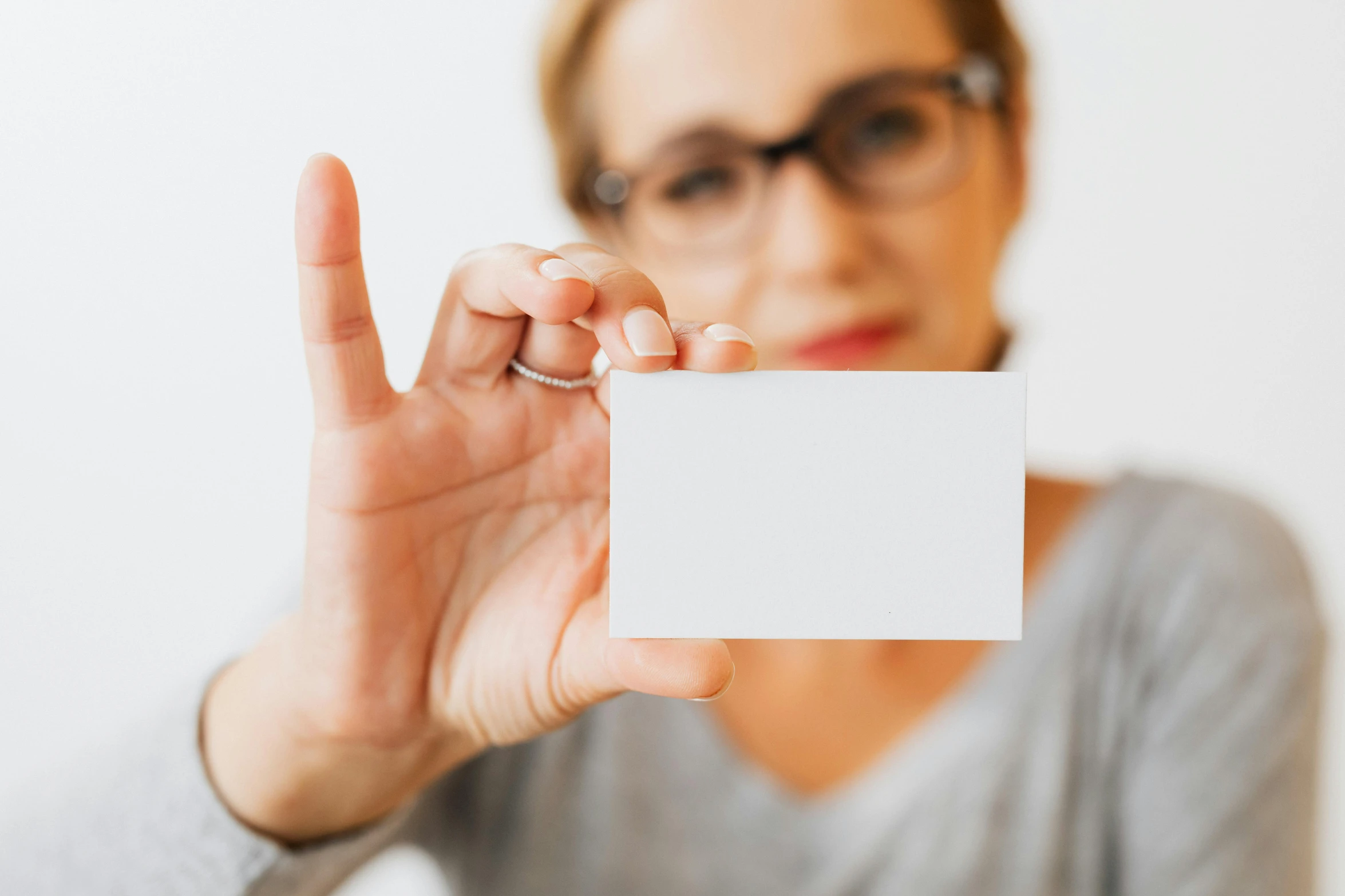 a woman holding up a blank business card, by Will Ellis, pexels, visual art, glossy white, nerdy appearance, fiona staples, transparent