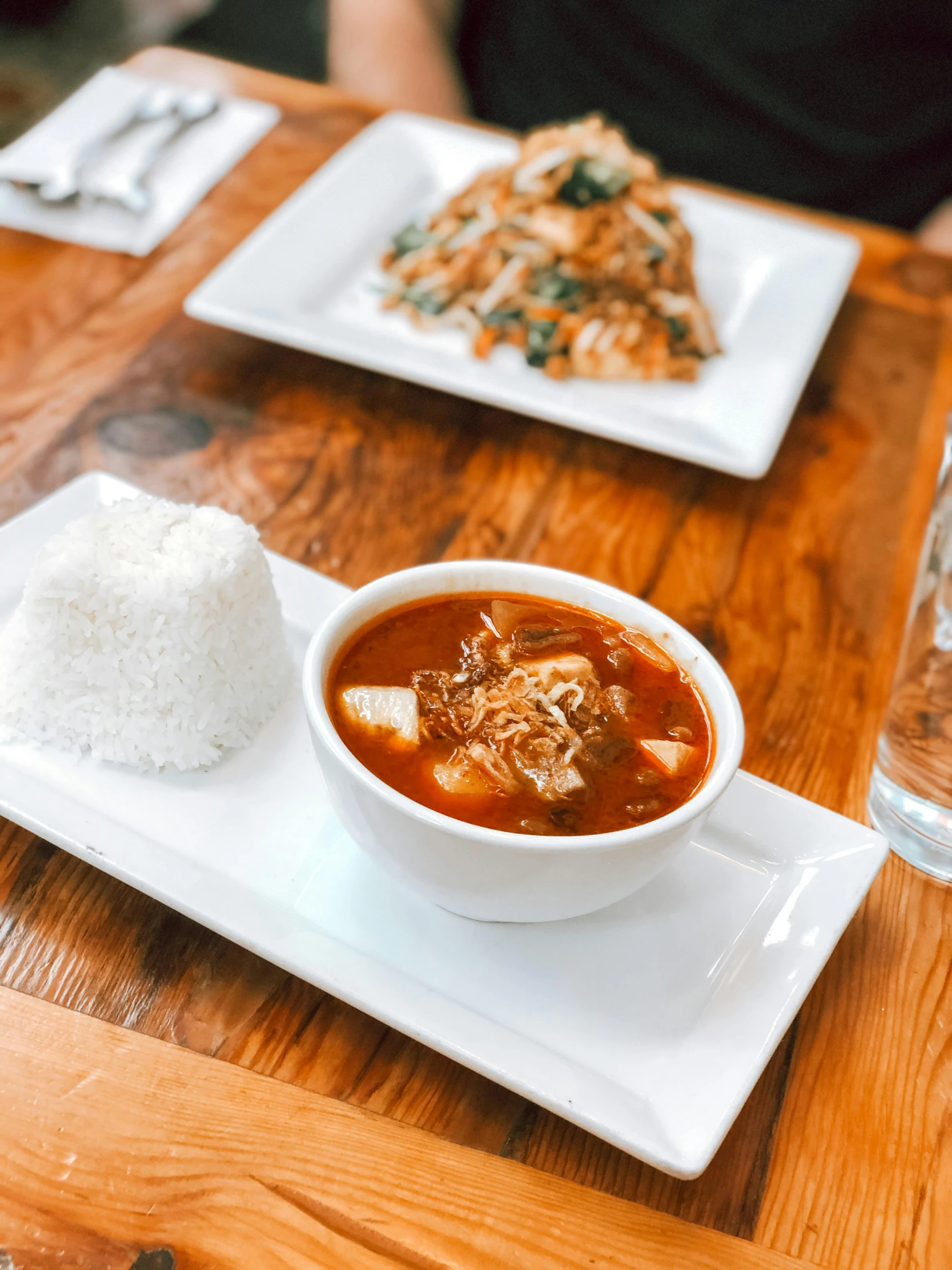 a bowl of soup and a plate of rice on a table, by Robbie Trevino, square, spicy, local foods, thumbnail
