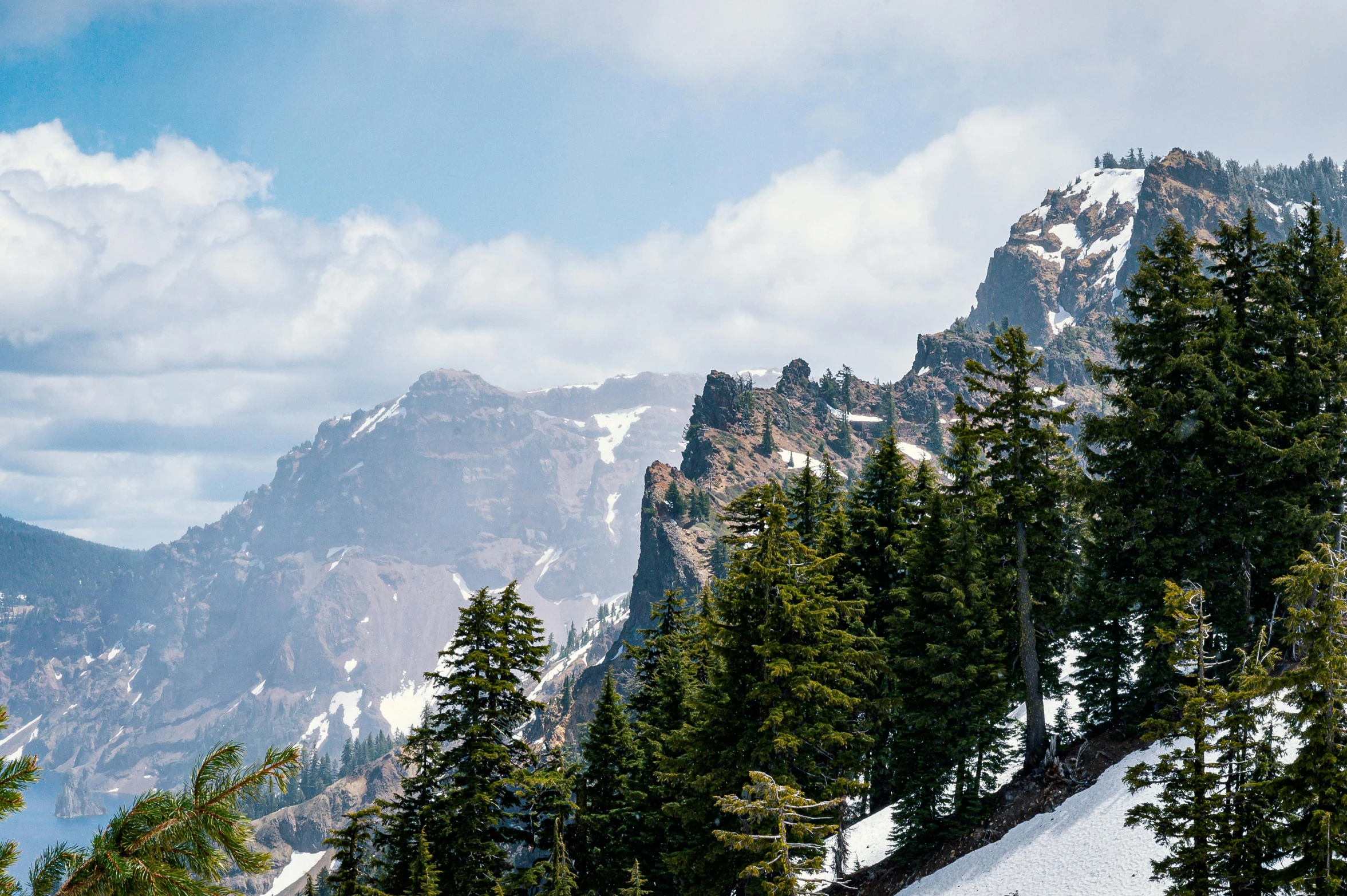 a group of people riding skis down a snow covered slope, by Doug Wildey, pexels contest winner, detailed trees and cliffs, crater lake, summer season, background image