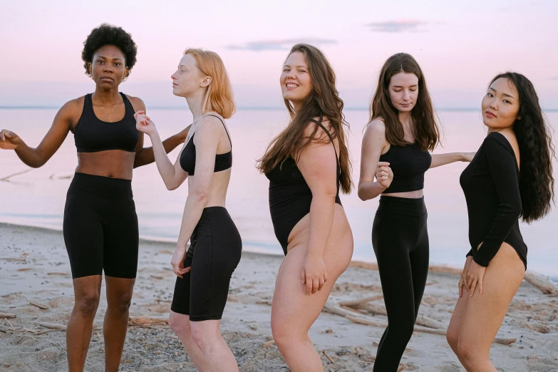 a group of women standing next to each other on a beach, by Emma Andijewska, unsplash, renaissance, black spandex, thick thighs, teenage girl, pale - skinned