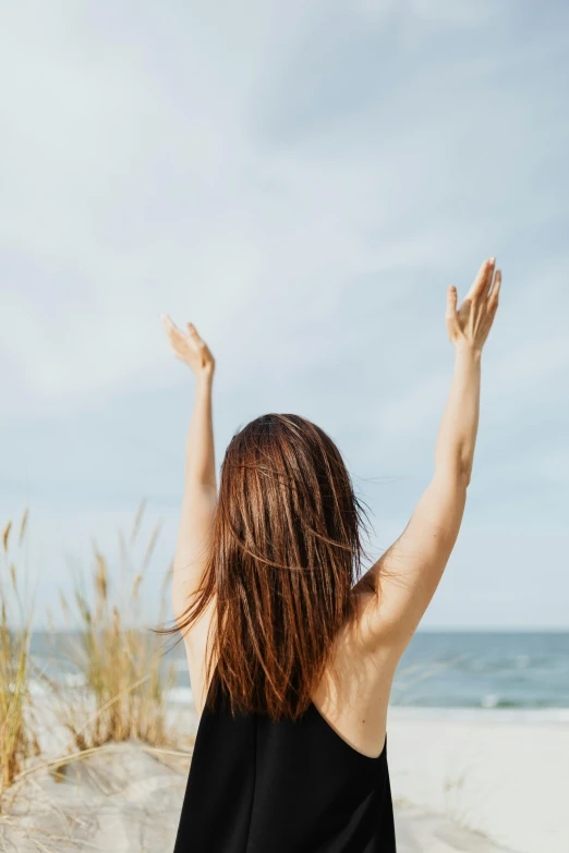 a woman standing on top of a sandy beach, hands in the air, girl with brown hair, top selection on unsplash, hairy arms