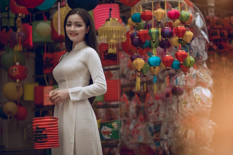 a woman standing in front of a display of lanterns, inspired by Lan Ying, pexels contest winner, ao dai, dilraba dilmurat, square, white