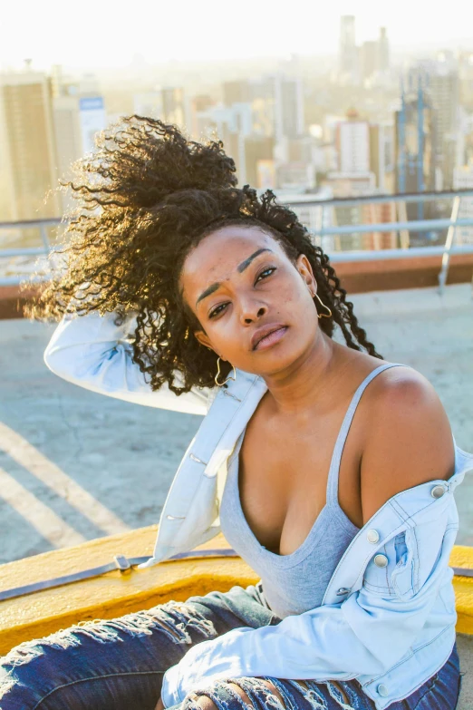 a woman sitting on top of a yellow bench, an album cover, by William Berra, trending on unsplash, renaissance, portrait of vanessa morgan, on rooftop, natural hair, promotional image