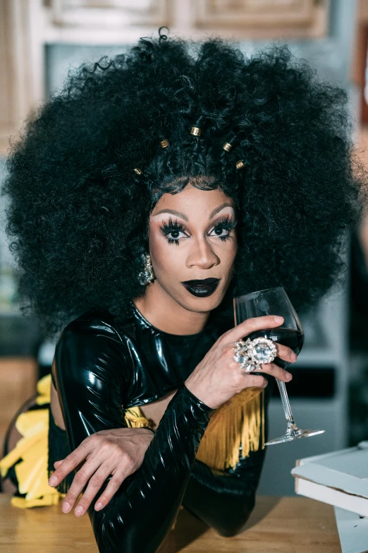 a woman sitting at a table with a glass of wine, an album cover, trending on pexels, renaissance, ru paul\'s drag race, looking straight to camera, panel of black, cheers